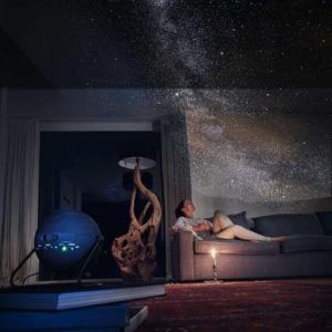 picture of woman sitting in a room with stars projected all over walls and ceiling