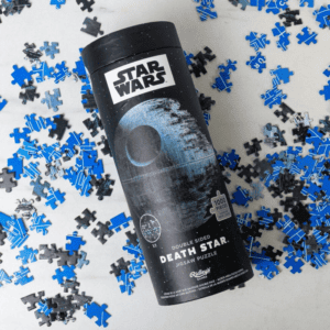 picture of Star Wars death star double sided puzzle in a cylindrical case with pieces scattered in the background